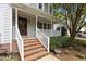 Inviting front porch with brick steps, a white railing, and lush greenery, enhancing curb appeal at 1210 Eastham Dr, Apex, NC 27502