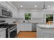Bright kitchen featuring white cabinets, stainless steel appliances, hardwood floors, and a window view to the backyard at 1210 Eastham Dr, Apex, NC 27502