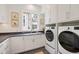 Bright laundry room with a modern washer and dryer, custom cabinets, and a large window at 1312 Duplin Rd, Raleigh, NC 27607