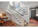 Elegant staircase with white balusters, a dark wood handrail, neutral runner, and stylish artwork adorning the walls at 1312 Duplin Rd, Raleigh, NC 27607