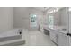 Bright bathroom featuring a soaking tub, tile floors, and a vanity with double sinks at 1408 Bridgeport Dr, Raleigh, NC 27615