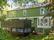 Green home exterior featuring a dark deck, large bay windows, and mature landscaping at 1408 Bridgeport Dr, Raleigh, NC 27615