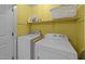 Laundry room features a white washer and dryer, storage shelves, and yellow walls at 1408 Bridgeport Dr, Raleigh, NC 27615