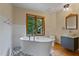 Relaxing bathroom featuring a white soaking tub, modern vanity, and serene backyard views at 145 Ryan Rd, Pittsboro, NC 27312