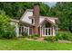 Exterior view highlighting the home's sunroom and entryway, surrounded by lush greenery at 145 Ryan Rd, Pittsboro, NC 27312