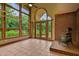 Bright sunroom features large grid windows, french doors to the yard, a brick accent wall, and a wood-burning stove at 145 Ryan Rd, Pittsboro, NC 27312