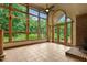 Sunroom features large grid windows, french doors, tile flooring, wood stove and access to the outdoor landscape at 145 Ryan Rd, Pittsboro, NC 27312