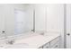 Bright bathroom featuring a double sink vanity, quartz countertop, and a mirror reflecting the shower stall at 173 Little Creek Dr, Lillington, NC 27546