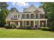 Charming two-story brick home featuring a welcoming front porch, black shutters, and manicured landscaping at 2328 Forestbluff Dr, Fuquay Varina, NC 27526