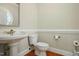 Cozy half bathroom featuring a pedestal sink, decorative mirror, wainscoting, and hardwood floors at 2328 Forestbluff Dr, Fuquay Varina, NC 27526