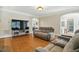 Open living room with hardwood floors, a large TV, comfortable seating, and an arched doorway to other living spaces at 2328 Forestbluff Dr, Fuquay Varina, NC 27526