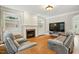 Cozy living room featuring a fireplace with built-in shelving, hardwood floors, and comfortable seating at 2328 Forestbluff Dr, Fuquay Varina, NC 27526