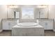 A soaking tub with dual vanity, lights, and mirrors at 2527 Sidewinder Ct, Apex, NC 27523
