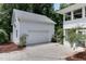 Detached garage with a driveway, attached to the main house by a quaint, covered walkway and green foliage at 325 Northfield Dr, Raleigh, NC 27609