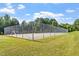 Outdoor tennis court surrounded by a high fence and lush green lawn, perfect for recreational play at 425 Hidden Cellars Dr, Holly Springs, NC 27540