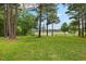 Serene backyard view featuring a lush green lawn, mature trees, and a glimpse of a pond at 4737 Uzzle Rd, Rougemont, NC 27572