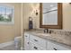 Bright bathroom featuring granite countertops, white cabinetry, decorative mirror and a window allowing natural light at 4737 Uzzle Rd, Rougemont, NC 27572