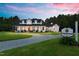 A two-story white home at dusk, featuring a charming wrap-around porch and a large lot at 4737 Uzzle Rd, Rougemont, NC 27572