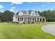 A beautiful two-story white home featuring a charming wrap-around porch and a lush lawn at 4737 Uzzle Rd, Rougemont, NC 27572