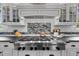 Close up of a large gas stovetop with a decorative backsplash and hood vent at 4737 Uzzle Rd, Rougemont, NC 27572