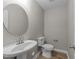 Neutral half-bathroom featuring a pedestal sink with a round mirror and wood-look flooring at 5012 Silverdene St, Raleigh, NC 27616