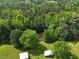 Picturesque landscape featuring outbuildings near a pond, bordered by lush green trees and open fields at 526 Bob Rainey Trl, Burlington, NC 27217