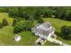 Aerial view of white home featuring lush landscaping, surrounded by green grass and mature trees at 526 Bob Rainey Trl, Burlington, NC 27217