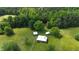 Aerial view of an outbuilding on a wooded lot, surrounded by lush trees and green pasture at 526 Bob Rainey Trl, Burlington, NC 27217