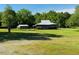 Large, open backyard featuring mature trees and outbuildings, perfect for outdoor activities and storage at 526 Bob Rainey Trl, Burlington, NC 27217