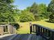 View from wooden deck shows grassy backyard with natural views of surrounding trees and greenery at 526 Bob Rainey Trl, Burlington, NC 27217