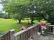 View from wooden deck shows grassy backyard with mature shade tree, flowers and potted plants at 526 Bob Rainey Trl, Burlington, NC 27217