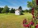 Scenic backyard view showcasing a shed and blooming flowers, offering a serene and picturesque setting at 526 Bob Rainey Trl, Burlington, NC 27217