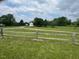 Spacious green field with distant view of house and barn. A wooden fence frames the open space at 526 Bob Rainey Trl, Burlington, NC 27217
