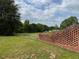 Brick fence surrounds an expansive green lawn, offering privacy and a serene view of the countryside at 526 Bob Rainey Trl, Burlington, NC 27217