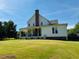 Exterior view of a farmhouse with a covered porch and a well-manicured lawn, with plenty of light at 526 Bob Rainey Trl, Burlington, NC 27217