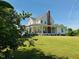 Exterior view of a farmhouse with a covered porch and a well-manicured lawn with lush greenery at 526 Bob Rainey Trl, Burlington, NC 27217