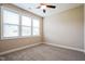 Neutral bedroom featuring three sunny windows, a ceiling fan, and plush carpeting at 67 Bornean Dr, Garner, NC 27529