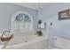 Bathtub with jets situated under a sunlit window, with a white tile surround at 7613 Percy Ct, Raleigh, NC 27613