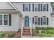 Close-up of home's entrance features a blue front door, brick steps, and mature landscaping at 7613 Percy Ct, Raleigh, NC 27613