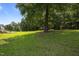 Lush backyard showcasing a spacious grassy area with large trees and a glimpse of the deck at 106 Oak Rd, Butner, NC 27509