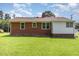 View of the backyard of the brick home with a well-maintained lawn, and a combination of brick and white siding at 1209 Bobbitt Dr, Garner, NC 27529