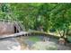 Scenic backyard featuring a wooden deck with stairs, a fire pit, a small storage shed, and mature trees at 1416 Bramble Dr, Durham, NC 27712