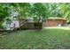 Expansive backyard featuring a wooden deck, lush greenery, and a brick and vinyl sided home at 1416 Bramble Dr, Durham, NC 27712