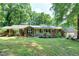 Charming brick home featuring a well-manicured lawn, mature trees, and a welcoming front porch, enhancing its curb appeal at 1416 Bramble Dr, Durham, NC 27712