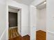 Open hallway featuring hardwood floors, neutral paint, an open white door, and a white bi-fold door at 1416 Bramble Dr, Durham, NC 27712