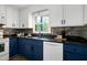 Close-up of the updated kitchen with two-tone cabinets, mosaic backsplash, and stainless steel dishwasher at 1416 Bramble Dr, Durham, NC 27712
