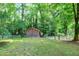 Exterior view of a wooden shed in a fenced in backyard with lush green trees at 1416 Bramble Dr, Durham, NC 27712