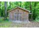 Outdoor storage shed with double doors and wooden construction, nestled among mature trees at 1416 Bramble Dr, Durham, NC 27712