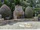 A stone outdoor fireplace is surrounded by manicured greenery, offering a cozy and inviting space for outdoor gatherings at 1512 Obrien Cir, Wake Forest, NC 27587