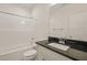 Bright bathroom features a shower, sink and vanity with a black countertop, and white cabinets at 156 Harmony Trl, Broadway, NC 27505